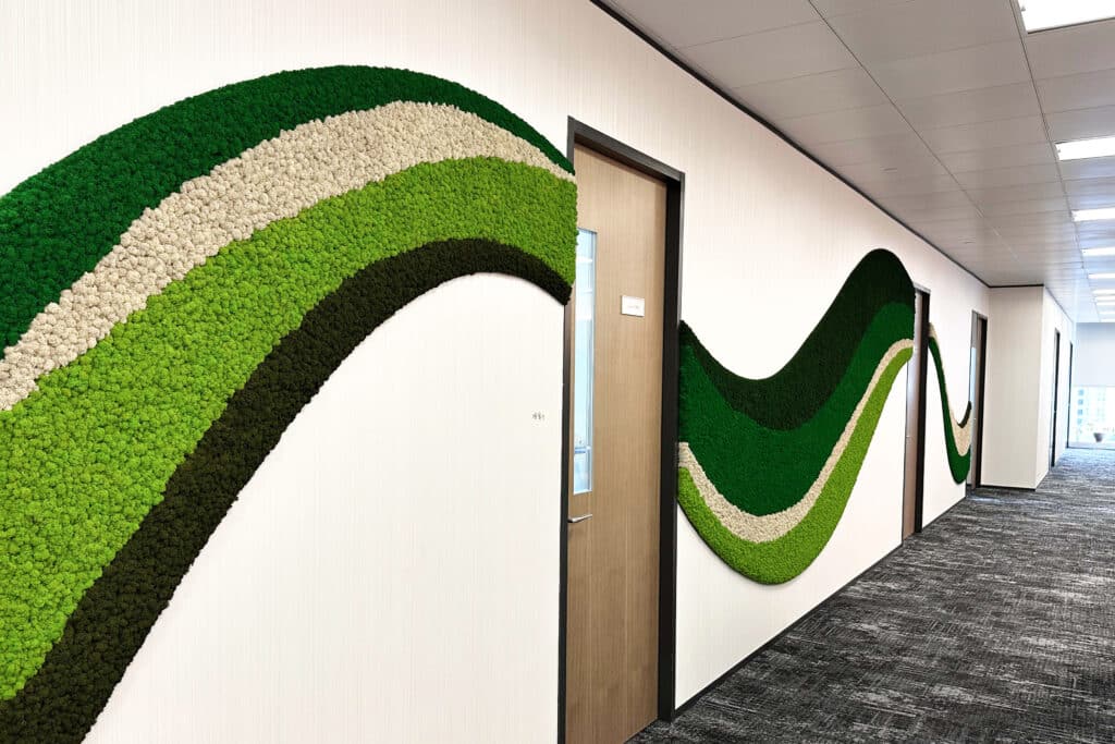 Reference image of Polarmoss Ltd. Office interior with large custom made colored moss element reaching through the whole wall. Shape of a wave. Four different colors of moss used. Produced by Polarmoss.